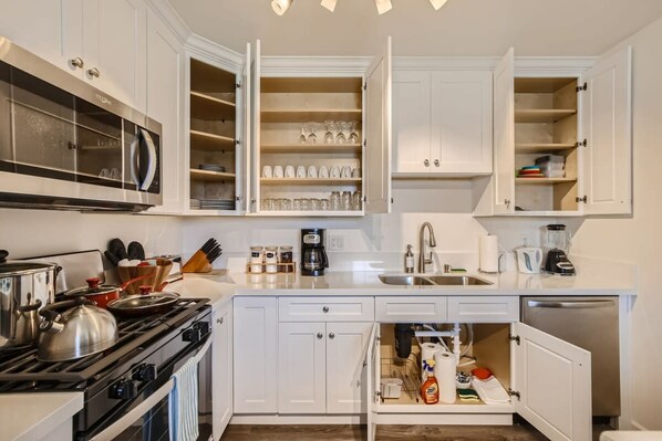 Una cocina moderna con armarios blancos, microondas integrado y estufa.