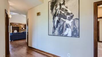 A hallway with a large abstract painting on the wall, a wooden floor, and a blue sofa in the background.
