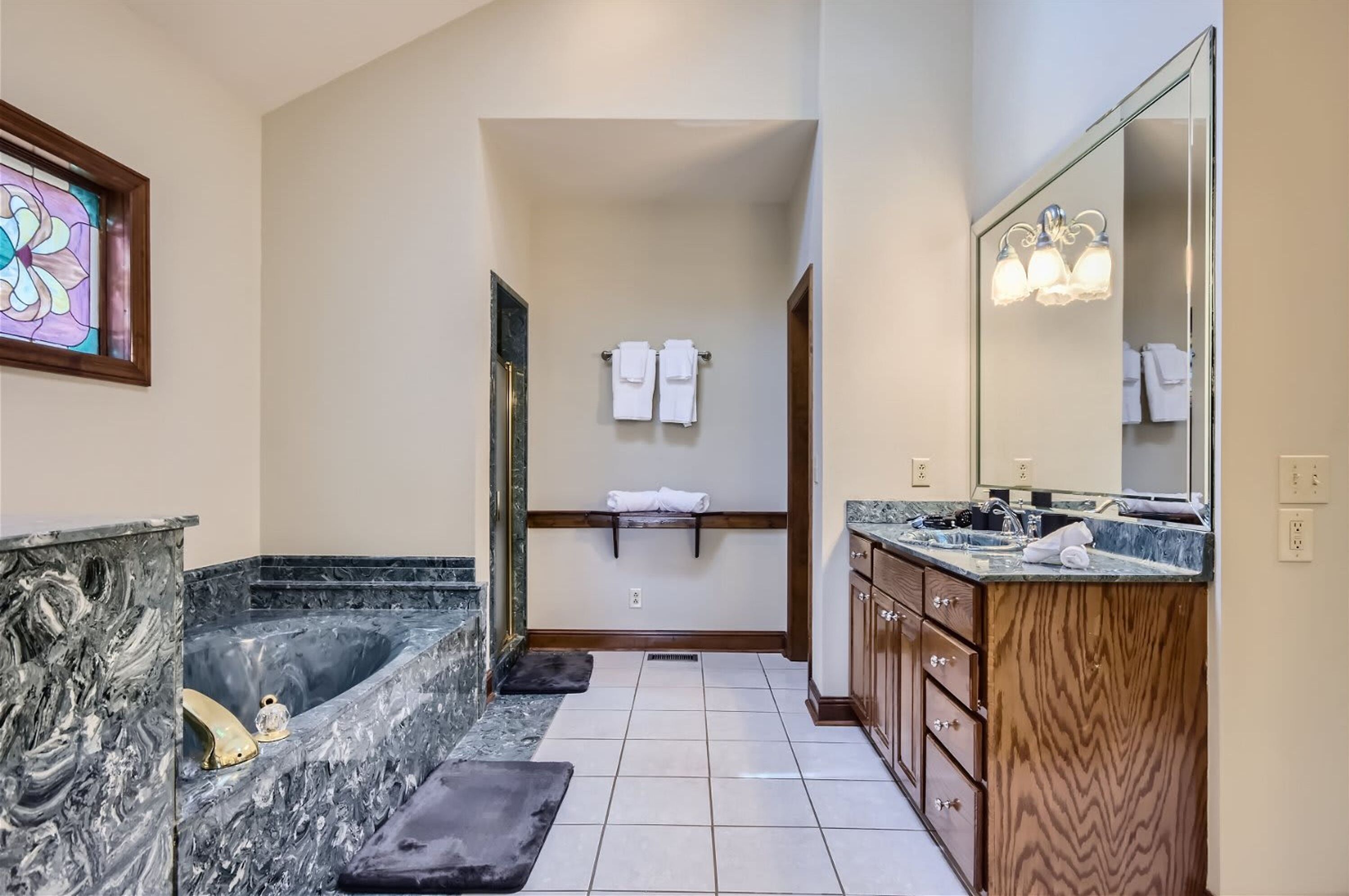 A bathroom with a marble sink, a large mirror, a bathtub, and a shower area.