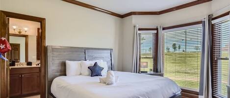 Un dormitorio ordenado con una cama grande, cabecera de madera, mesita de noche y una ventana con persianas.