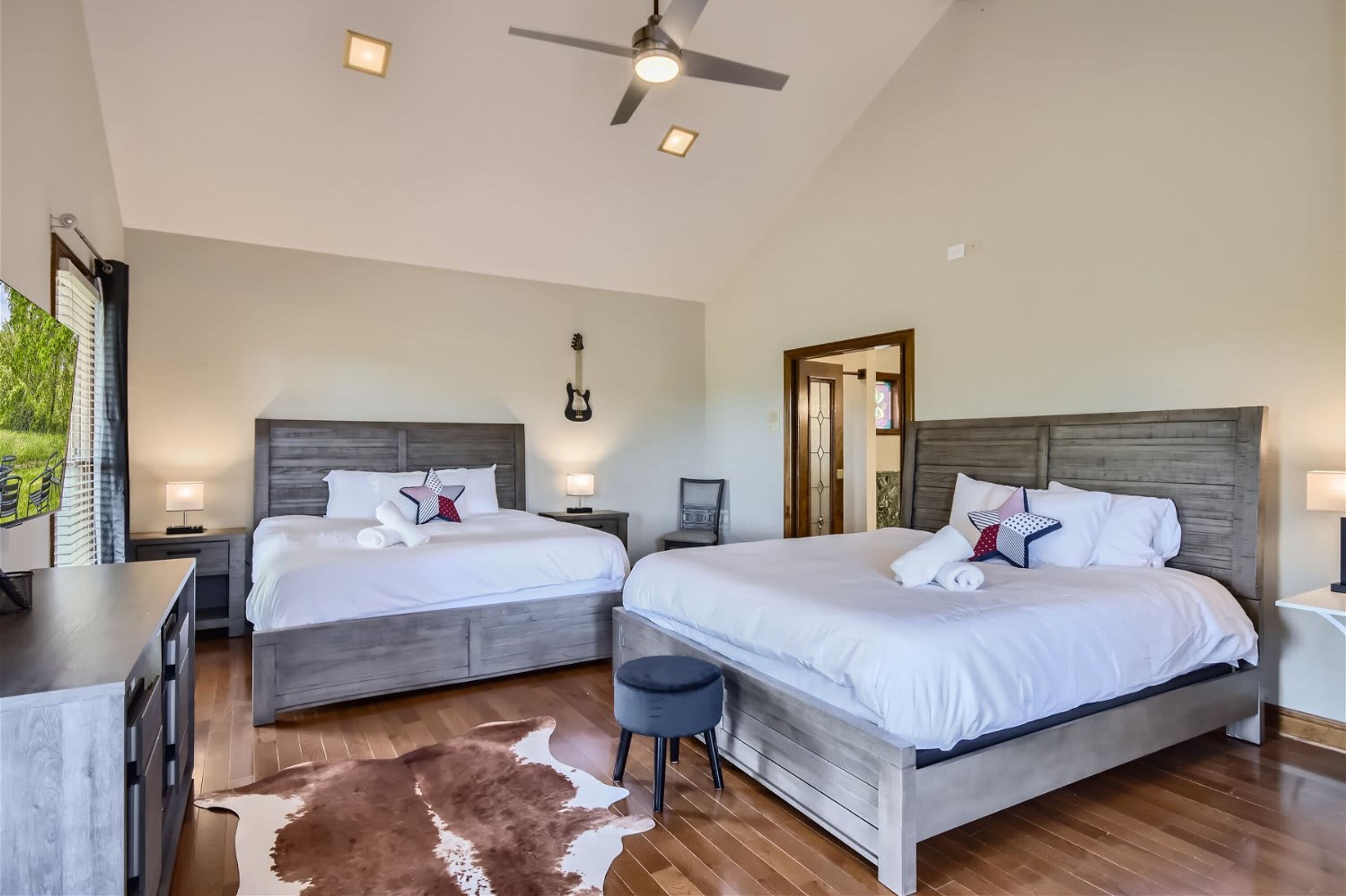 Un dormitorio con dos camas, un ventilador de techo y suelo de madera.