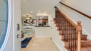 Ein Wohnzimmer mit einer Holztreppe, einer Küche im Hintergrund und einem Essbereich.