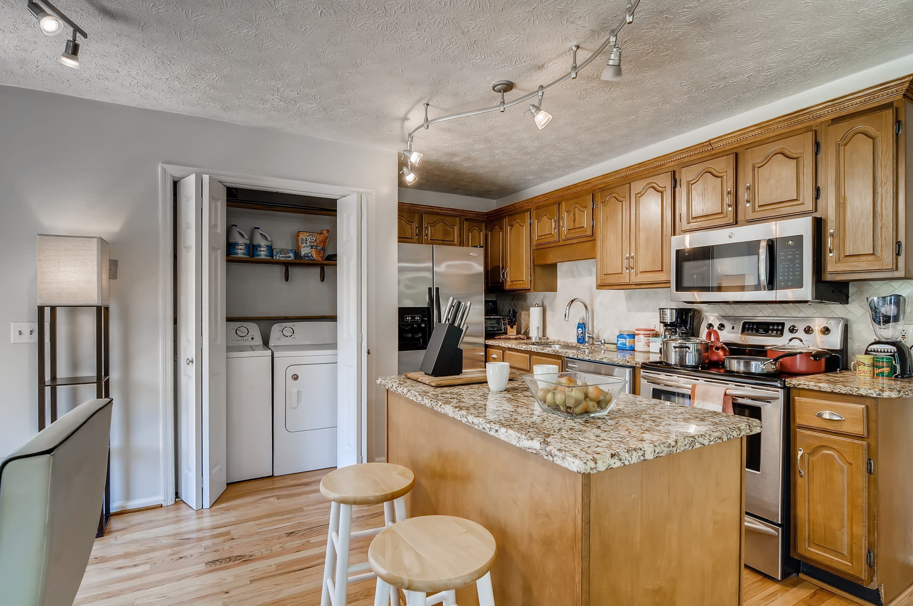 A kitchen with wooden cabinets, a stainless steel refrigerator, a microwave, and a granite countertop.