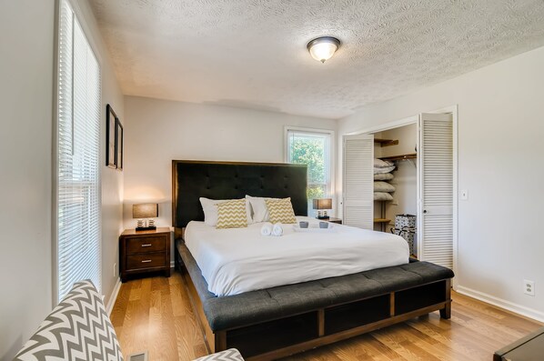 A bedroom with a large bed, wooden floor, and a walk-in closet.