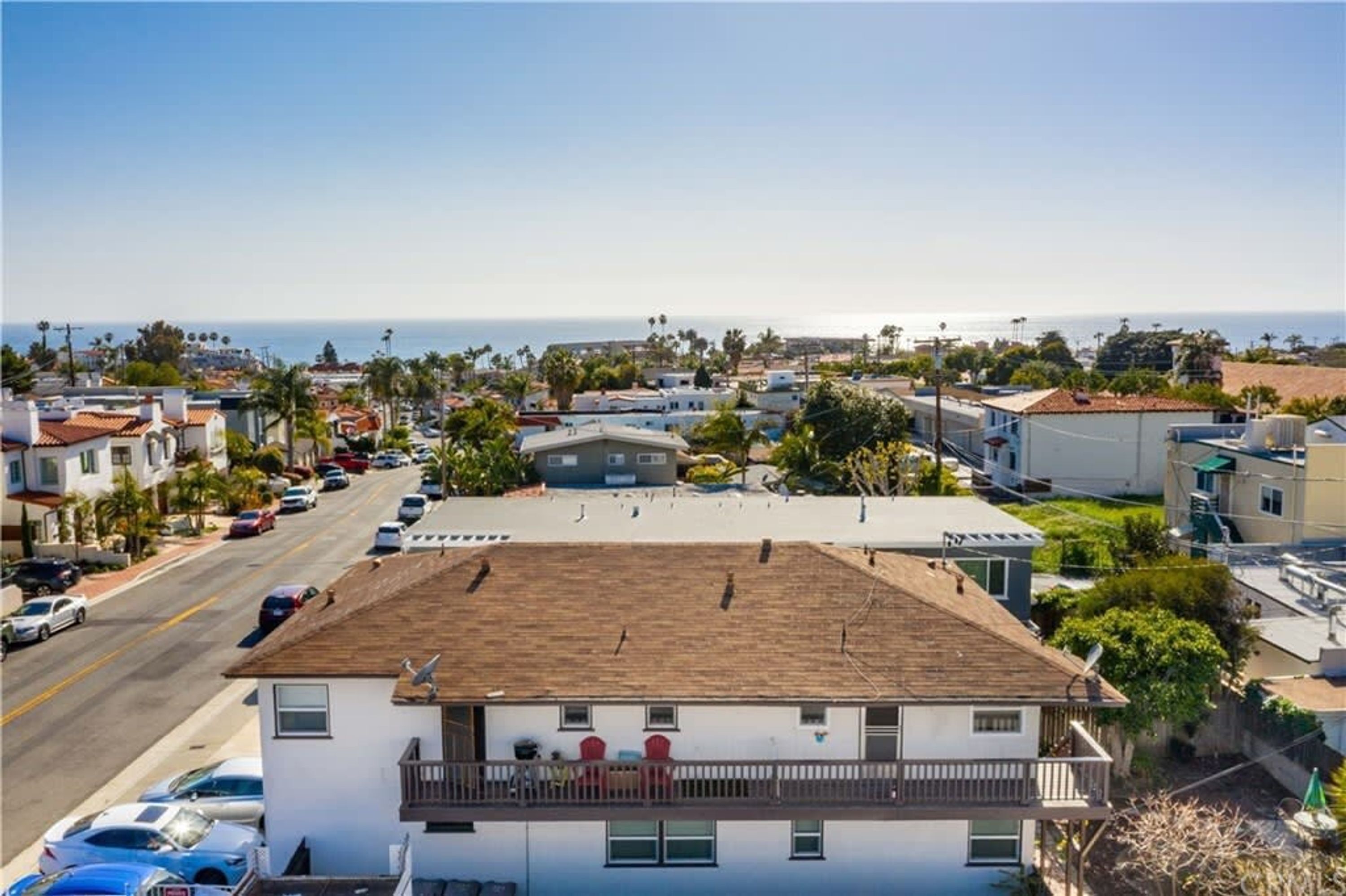 A coastal residential area with a white building featuring a balcony and satellite dishes.