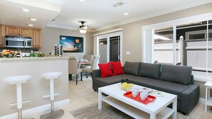 A modern kitchen with a microwave, bar stools, and a dining area with a table and chairs. - Costa Mesa -newport- Patio - Free Parking-cm-2 (Costa Mesa)