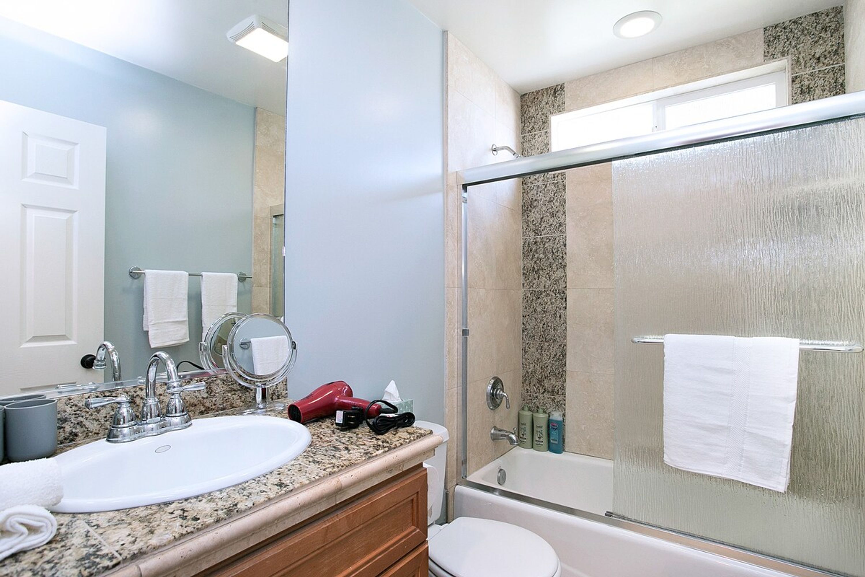 A bathroom with a sink, mirror, and glass shower enclosure.