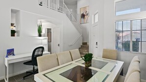 Un intérieur moderne comprenant un coin repas, un escalier et une grande fenêtre.