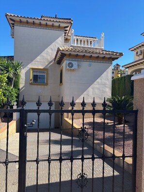 Un bâtiment à la façade blanche, doté d’un balcon avec une balustrade blanche et d’une porte ornée d’un motif décoratif.