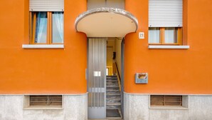 Una entrada de edificio con una escalera cubierta que conduce a una puerta con una celosía metálica.