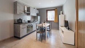 Une cuisine moderne avec un coin repas, comprenant une table et des chaises, un four à micro-ondes et une bouteille de vin.