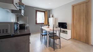 Une cuisine moderne avec un coin repas, un téléviseur et une porte en bois.