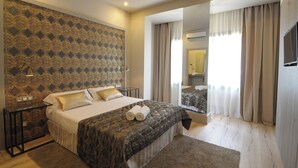 A hotel room with a large bed, a nightstand, a mirror, and a view of the bathroom.