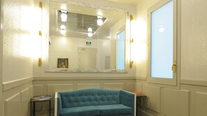 A room with a large mirror, a blue sofa, and a small table.