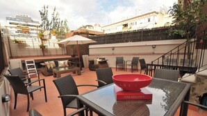 An outdoor patio with wicker furniture, a glass table, and a red bowl.