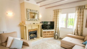 A living room with a fireplace, a television, and two sofas.
