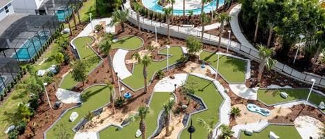 A golf course with multiple holes, surrounded by a pool area and palm trees.