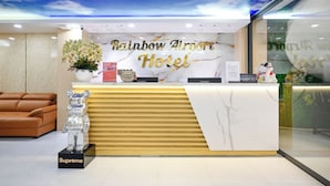 Ein Hotelrezeptionstresen mit Marmorplatte, einer Bärenskulptur und einer Decke mit Wolkenmotiv.