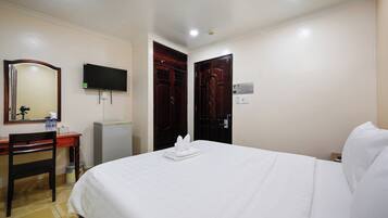 A hotel room with a bed, a desk, a chair, a television, and a wardrobe.