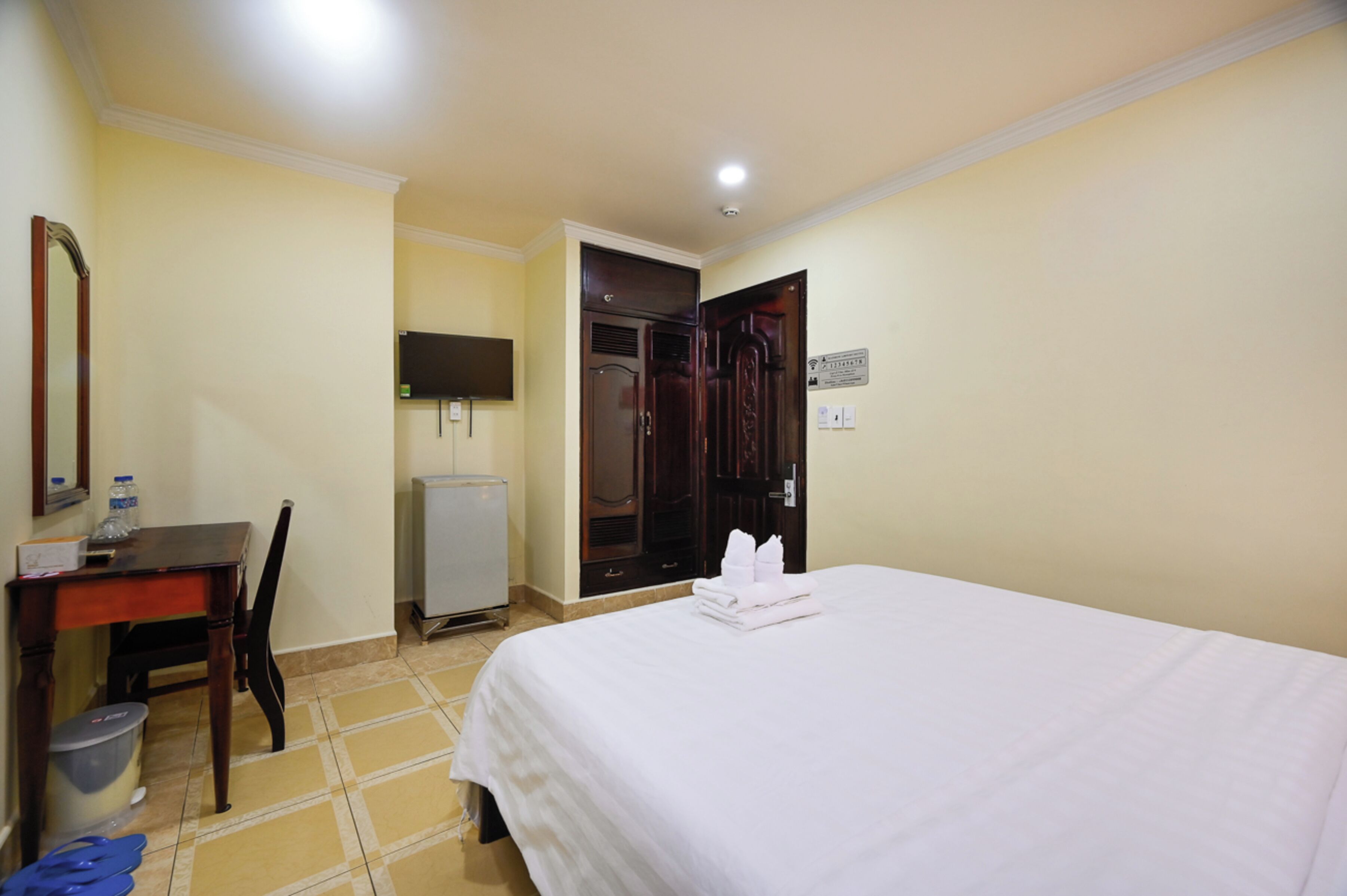 Una habitación de hotel con cama, escritorio, silla, televisión y armario.