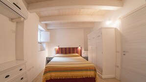 A bedroom with a wooden ceiling, a bed with a striped bedspread, a wardrobe, and a small bedside table. - The Landing, in the heart of downtown, a stone's throw from ferry and main square (Carloforte)