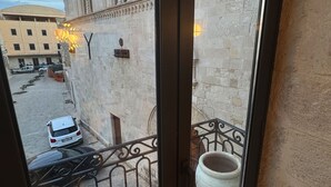 A view from a balcony with a wrought iron railing, a large white vase, and a building with detailed stonework. - Montalto Luxury House (Siracusa)