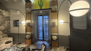 A room with a cactus mural, a sofa, a coffee table, and a door leading outside. - Montalto Luxury House (Siracusa)