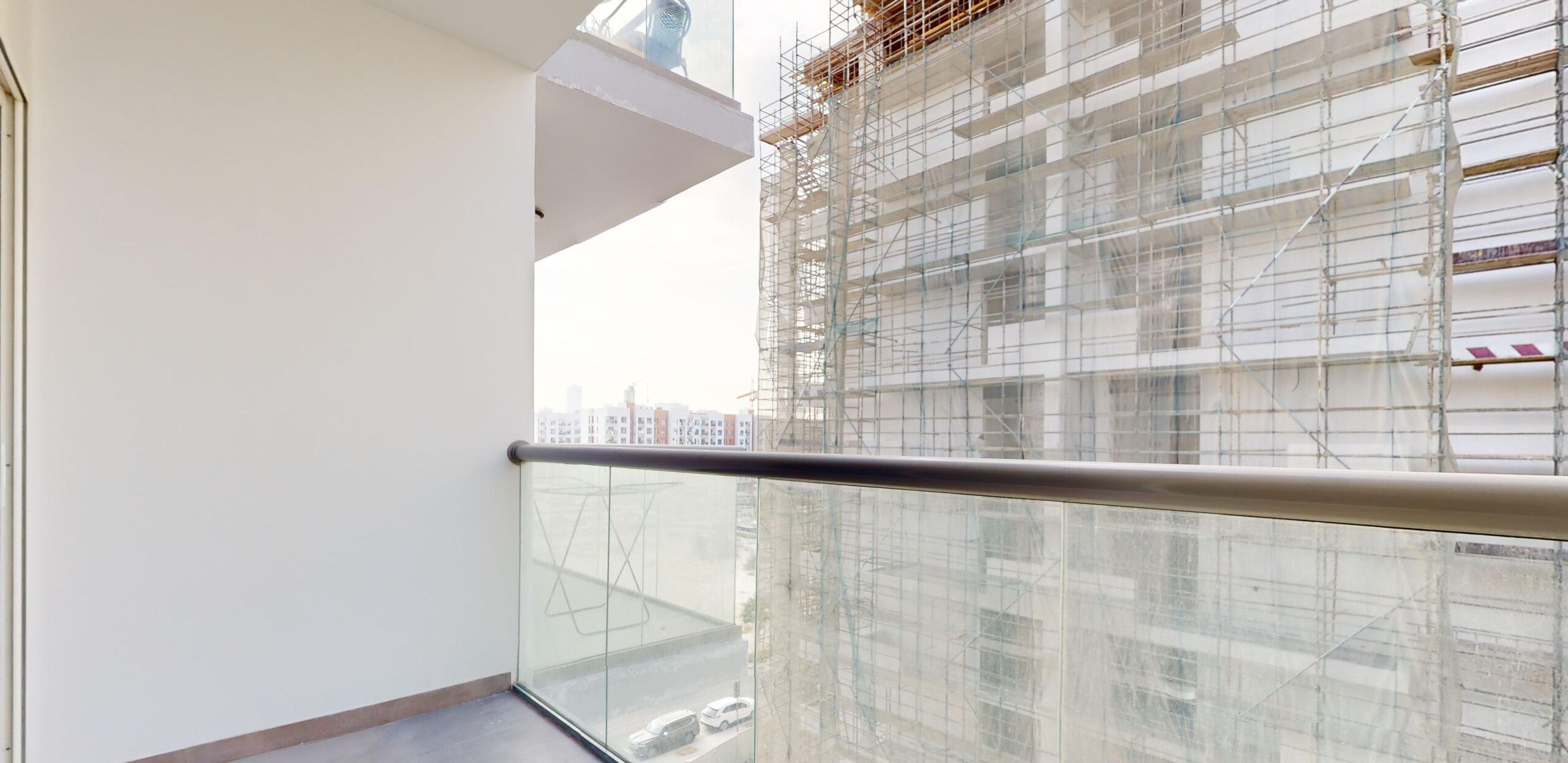 A balcony with a clear view of a building under construction with scaffolding.