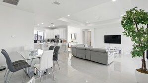 Un espacio moderno tipo sala de estar con comedor, cocina y un sofá gris grande.