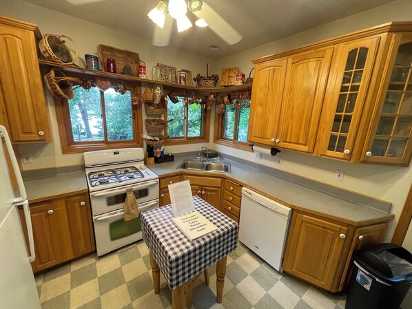 A kitchen with wooden cabinets, a stove, a sink, and a table with a placemat.