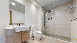 A modern bathroom with a glass-enclosed shower, a white sink, and a toilet. - Stylish Retreat with Scenic Views in Bloom Towers (Dubai)
