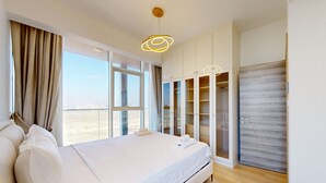 A modern bedroom with a large bed, a wardrobe with glass doors, and a view of the city. - Stylish Retreat with Scenic Views in Bloom Towers (Dubai)