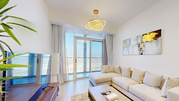 A modern living room with a sectional sofa, a coffee table, and a large window offering a view of the city. - Stylish Retreat with Scenic Views in Bloom Towers (Dubai)