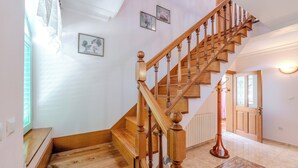 A wooden staircase with a handrail, a wooden bench at the bottom, and a patterned rug on the floor. - Seaside Garden Villa Kožino (Kožino)