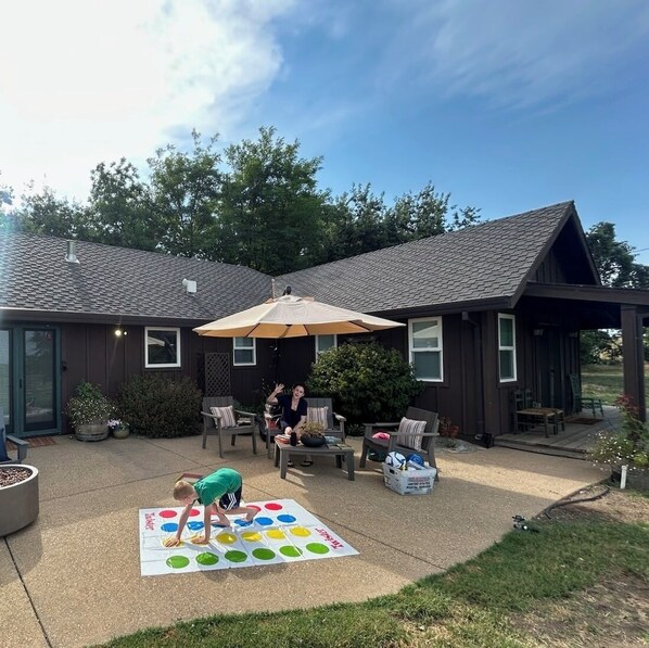 A patio area with a table and chairs, a large umbrella, and a game board.