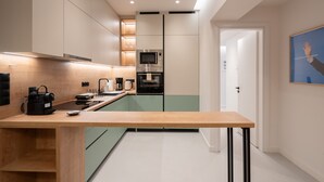 A modern kitchen with a wooden countertop, built-in appliances, and a minimalist design. - LIV - Modern Heavenly Retreat in Exarcheia (Athens)