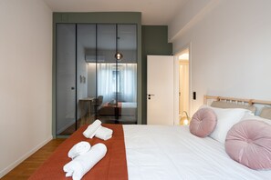 A modern hotel room with a large bed, a wooden headboard, and a glass partition separating the bedroom from the bathroom. - LIV - Modern Heavenly Retreat in Exarcheia (Athens)