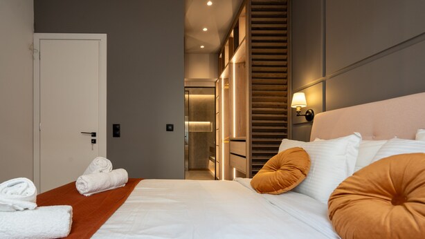 A hotel room with a large bed, a wooden headboard, and a view of the hallway. - LIV - Modern Heavenly Retreat in Exarcheia (Athens)