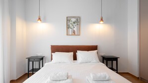 A neatly made bed with white linens, two bedside tables, and a framed picture on the wall. - LIV - Captivating Apartment in Pagrati (Athens)