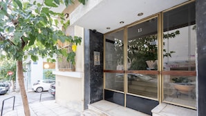 A building entrance with a glass door, steps, and a potted plant. - LIV - Captivating Apartment in Pagrati (Athens)