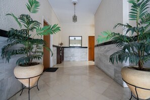 A hallway with potted plants, a marble floor, a wooden door, and a mirror on the wall. - LIV - Captivating Apartment in Pagrati (Athens)