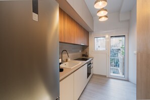 A modern kitchen with a built-in oven, a sink, and a window overlooking a balcony. - LIV - Captivating Apartment in Pagrati (Athens)