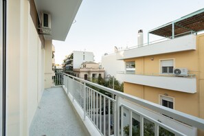 A narrow balcony with a white railing, overlooking a street with buildings and a clear sky. - LIV - Captivating Apartment in Pagrati (Athens)