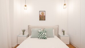 Camera da letto con un letto, due comodini, un tavolino, un'opera d'arte appesa al muro e due lampade a sospensione.