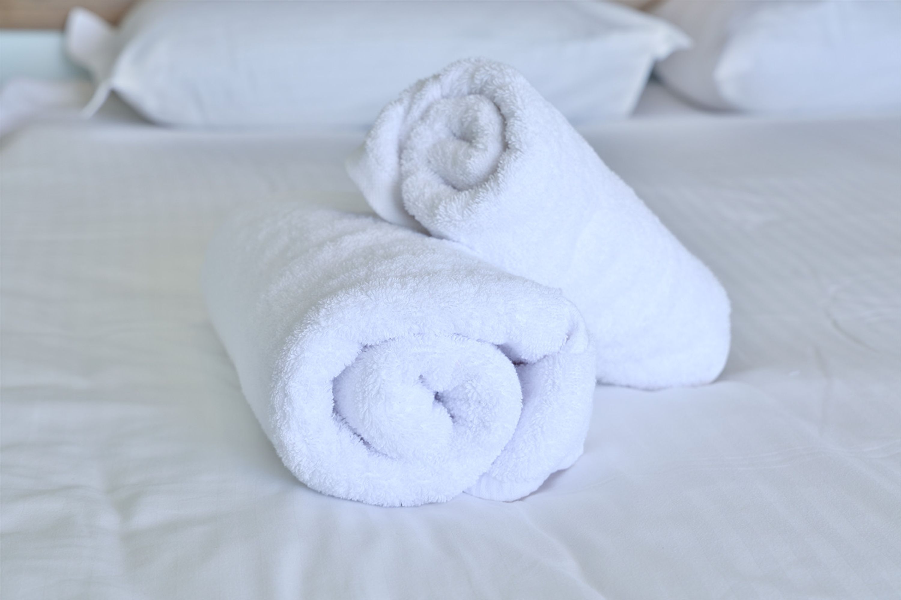 Un lit bien fait, avec du linge de lit blanc et des serviettes blanches roulées.