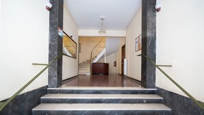 A marble staircase leading to a landing with a ceiling fan, a wooden door, and a wall-mounted light fixture. - LIV - Cozy Urban Apartment in Pagrati (Athens)
