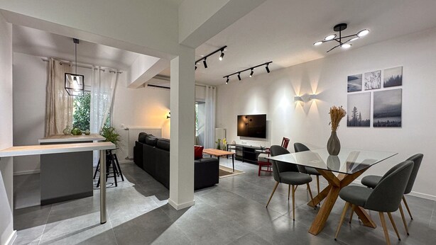 A modern living room with a glass dining table, black sofa, and a TV. - LIV - Modern Comfort Oasis in Pagrati (Kaisariani)
