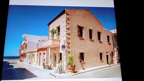 A coastal building with a balcony, a no parking sign, and potted plants.
