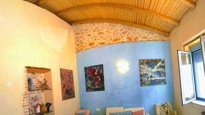 A room with a curved ceiling, a stone wall, and two paintings.