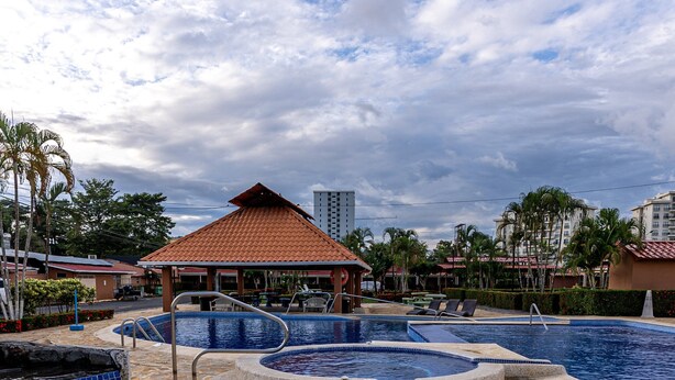 A swimming pool with a hot tub, a gazebo, and palm trees. - Villas Paraiso B52 (Jacó)